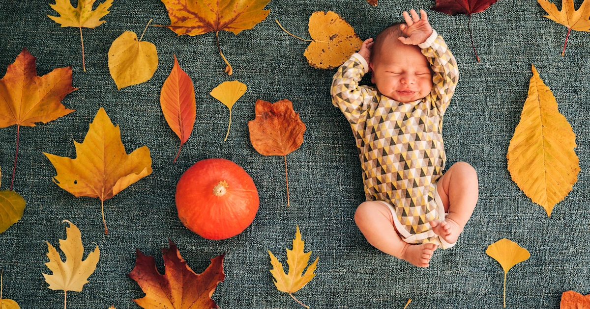 Baby dressed in cozy fall outfit sitting among pumpkins