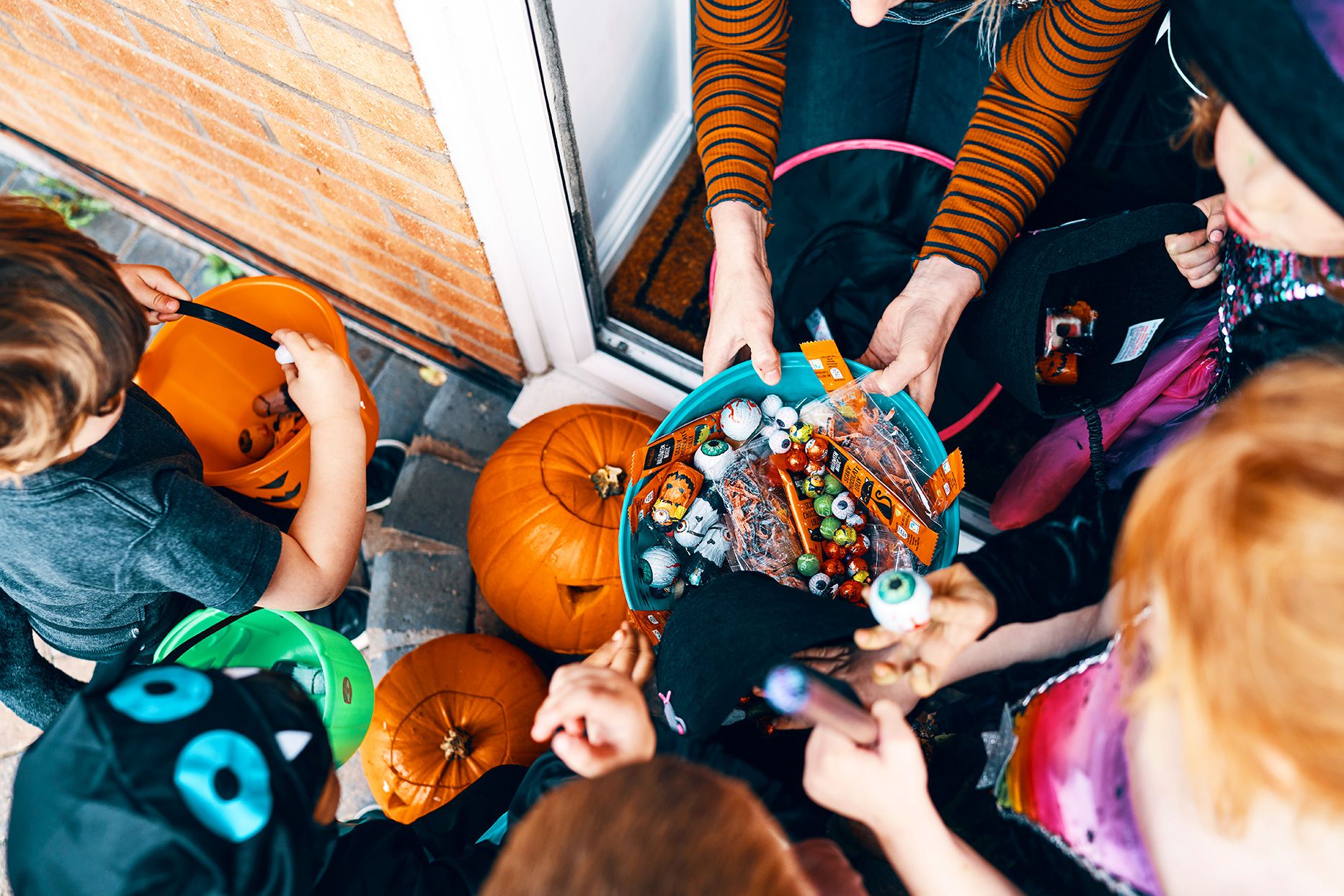 Kids holding bright trick-or-treat buckets on Halloween night