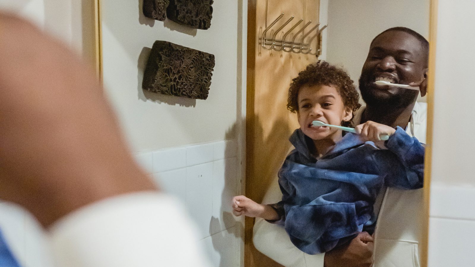 Parent helping a toddler during a morning routine while also caring for a newborn